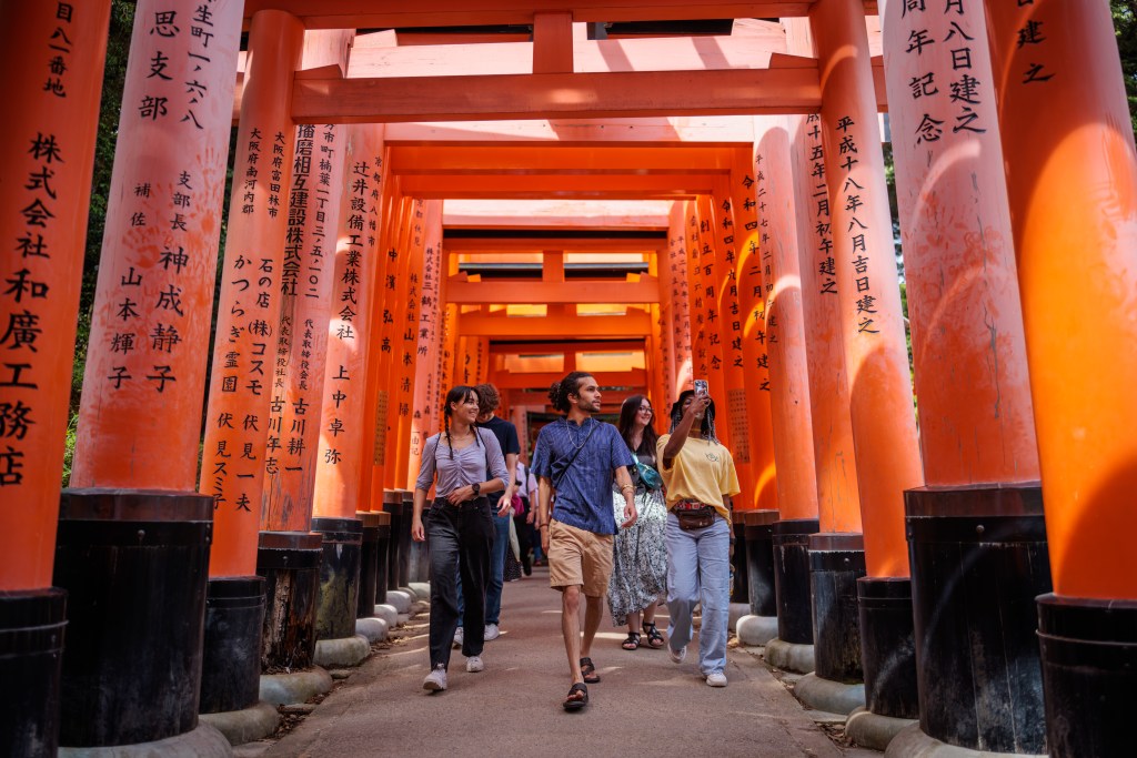Three students walk through the grounds of Fushimi Inari Shrine in Kyoto, Japan.